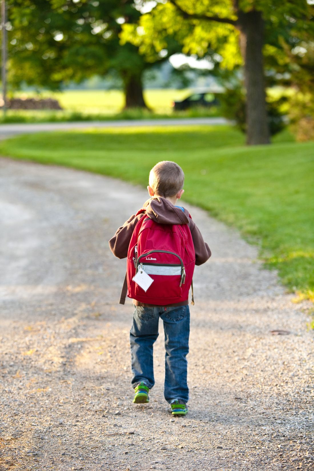 Child with a red backpack walking alone toward school on a tree-lined path — back-to-school anxiety in Monterey County, CA